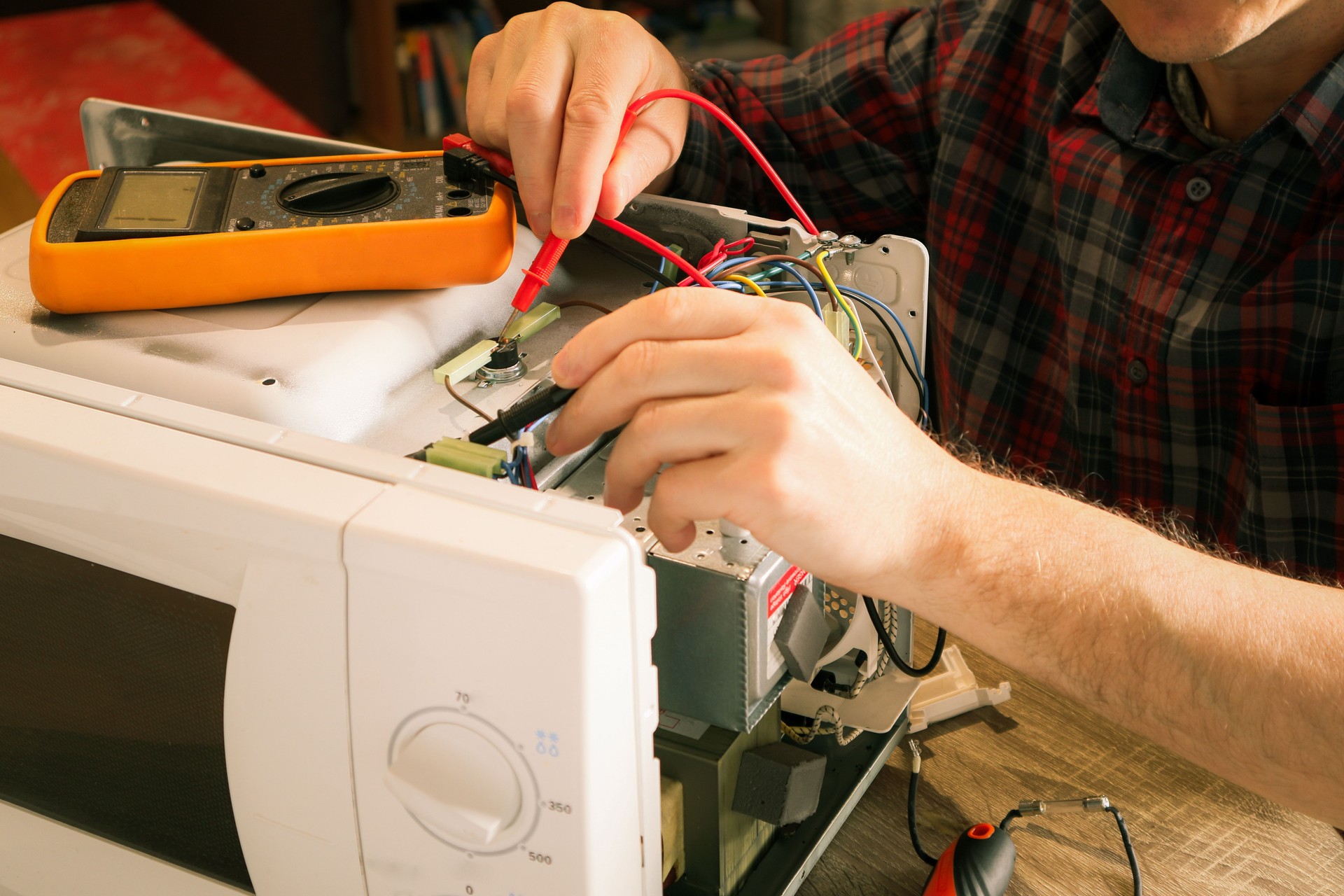 Diagnostics repair of microwave oven. A repair engineer uses a multimeter to check the circuits of a microwave oven, looking for a fault.