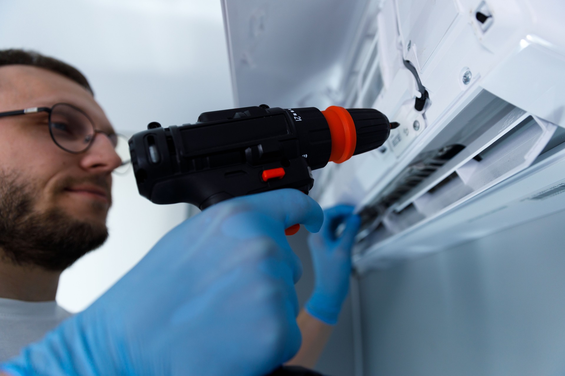 Expert Technician Performing Maintenance on an Air Conditioning Unit with a Power Drill for Efficient Service Excellence and Quality Assurance in Indoor Environments